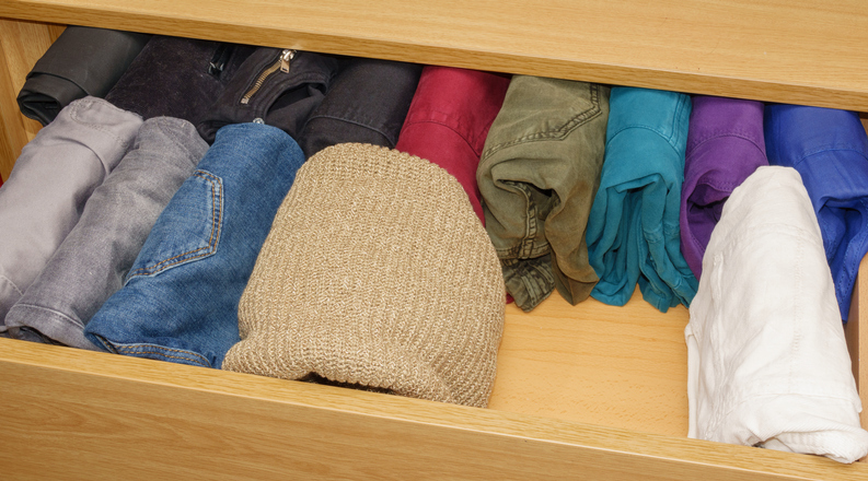 Background top view of well organized open drawer with trousers and wool sweaters