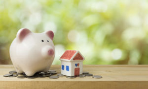 A piggy bank and a miniature house a visual representation of saving up money for your home down payment