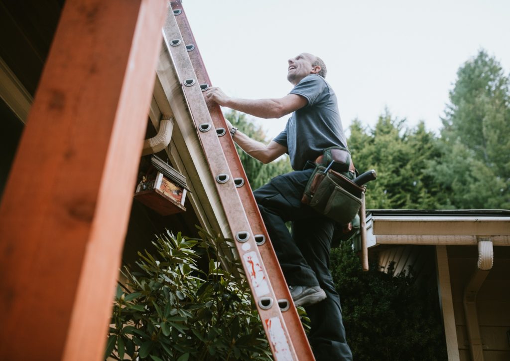 Man climbing ladder for roof repair