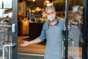 business owner wearing a facemask and reopening his cafe