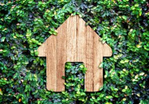 Wooden house icon on green leaves