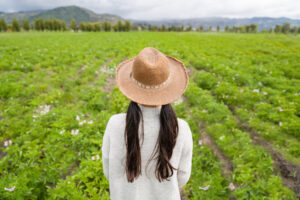 Latin American girl at a farm looking at the potato crop while wearing a hat agriculture concepts