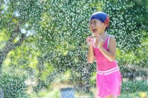 a little girl enjoying the water sprinkler
