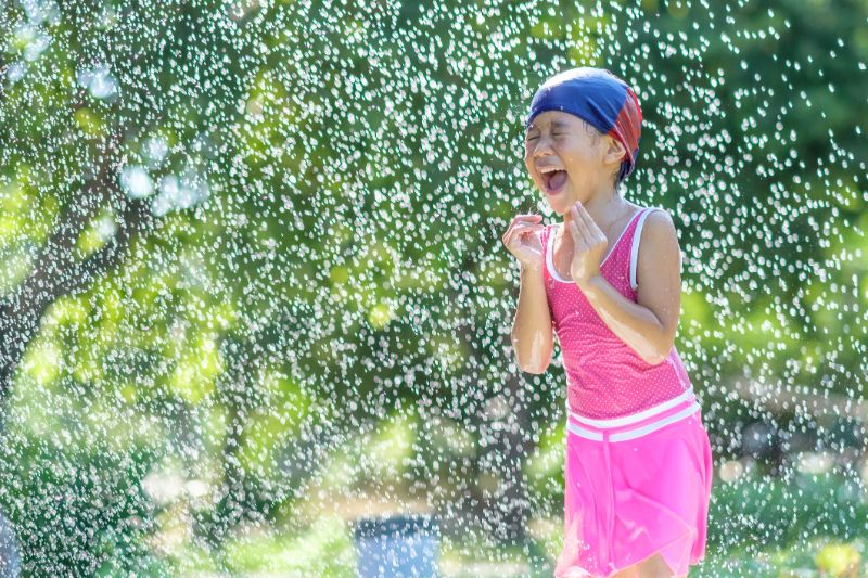 a little girl enjoying the water sprinkler